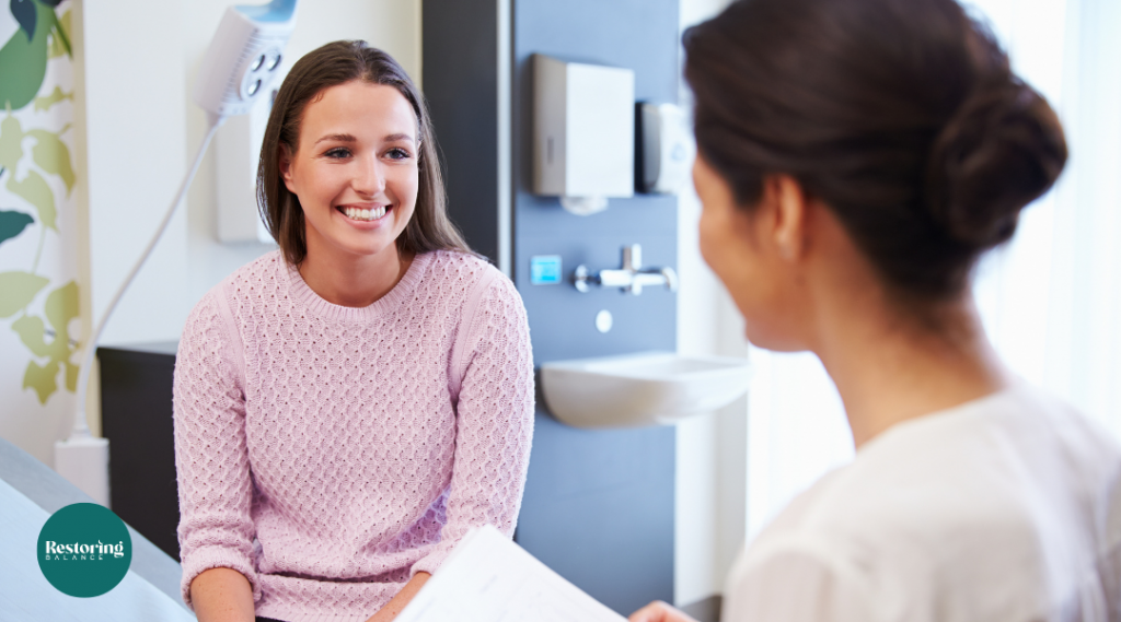 A smiling female talking to a medical professional